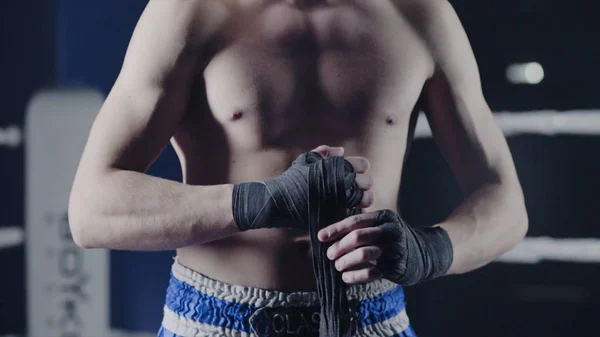 Fechamento de um lutador de artes marciais mistas envolvendo suas mãos antes de uma luta. Boxer envolve sua mão uma bandagem vermelha antes do figh — Fotografia de Stock