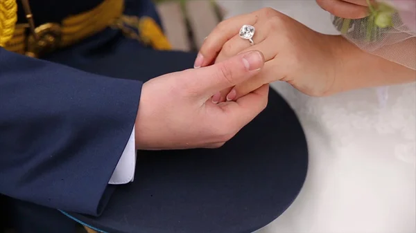 Young married couple holding hands, ceremony wedding day. Close up Groom Put the Wedding Ring on bride