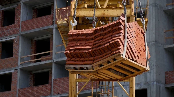 Vinç ve bina inşaat alanında mavi gökyüzü karşı. ağır yük inşaat yapım aşamasında tuğla vinç kanca asılı