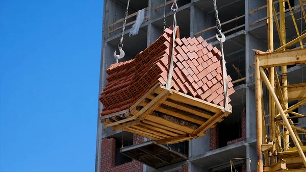 Vinç ve bina inşaat alanında mavi gökyüzü karşı. ağır yük inşaat yapım aşamasında tuğla vinç kanca asılı
