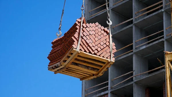 Vinç ve bina inşaat alanında mavi gökyüzü karşı. ağır yük inşaat yapım aşamasında tuğla vinç kanca asılı