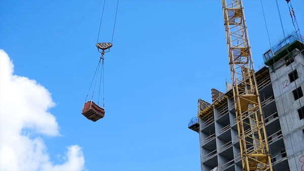 Vinç ve bina inşaat alanında mavi gökyüzü karşı. ağır yük inşaat yapım aşamasında tuğla vinç kanca asılı