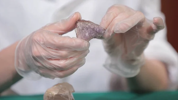 Natural stone amethyst or another mineral, stone. Wild amethyst in female hands in white gloves. Rock stone in hands