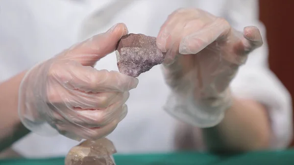 Natural stone amethyst or another mineral, stone. Wild amethyst in female hands in white gloves. Rock stone in hands