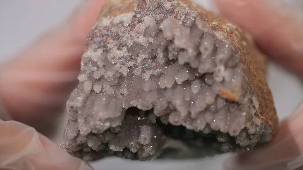 Bright grey ruby crystal ore in hands with gloves. Crystallization is the natural or artificial process by which a solid forms in laboratory.