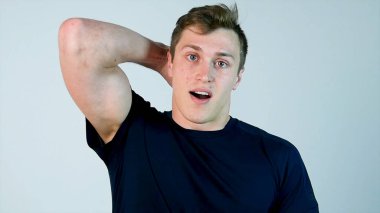 Casual giyim tutma ağız açık ve kamera beyaz arka plan karşı dururken bakarken şaşırmış genç adam