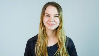 Genç, güzel, neşeli, gülümseyen kız beyaz arka planda kameraya bakıyor.