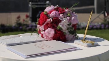 Menekşe ve mor çiçekler ile yeni evliler için dekorasyon düğün Arch kayıt tablosu ile. Kayıt defteri pembe çiçeklerle süslenmiş beyaz masa üzerinde duran güneş ışığı yanar.