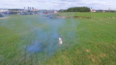 Çift havadan anket ellerde renkli duman ile alanda yürümek. Adam ve kadın üzerinde uçan renkli duman kullanarak alan üzerinden çalıştırın. Aşıklar alan üzerinden kırmızı ve pembe duman ile çalışan