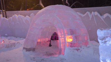 İnsanlar ve bebek yürümek içinde buz şehir sırasında kar yağışı. Çocuklar oynar şehirde buz, kar Köyü Igloo adlı. . Yeni yıl buz aydınlatılmış bir kasaba. Buz ve kar dünya