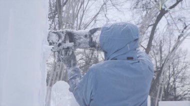 Heykeltıraş buz oyma görünümü. Hareket. Testere ile buz kes. Kes ve kar heykelini yap. Buzlu suyu balta ile kesiyorum. Buz heykel oyma. V-log