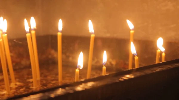 Encender una vela con una cerilla para conseguir una vela romántica. Increíbles andles y candelabros están sobre la mesa. Mantenga las luces con el trasfondo pacífico de la ceremonia religiosa . —  Fotos de Stock