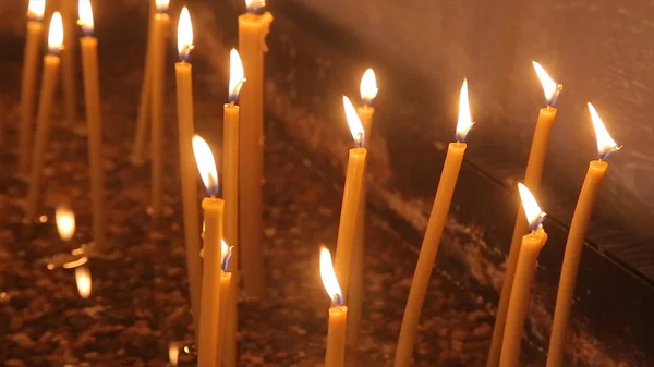 Encender una vela con una cerilla para conseguir una vela romántica. Increíbles andles y candelabros están sobre la mesa. Mantenga las luces con el trasfondo pacífico de la ceremonia religiosa . —  Fotos de Stock