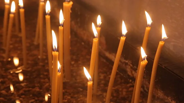 Encender una vela con una cerilla para conseguir una vela romántica. Increíbles andles y candelabros están sobre la mesa. Mantenga las luces con el trasfondo pacífico de la ceremonia religiosa . —  Fotos de Stock