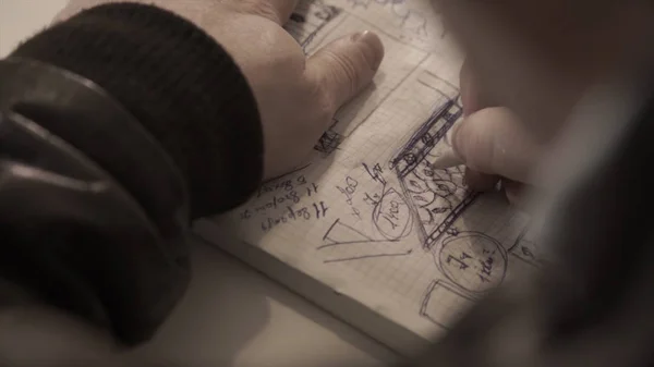 Чоловік малює в блокноті, беручи нотатки, людина пише в щоденнику, блокноті. Написання — стокове фото