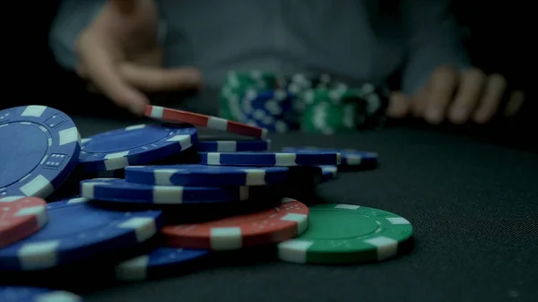 Zbliżenie: człowiek rzuca żetony do pokera w zwolnionym tempie. Zbliżenie dłoni z rzucania żetony do gry na czarnym tle. Zwiększenie jego stawki rzuca żetony na stole do gry w pokera. — Zdjęcie stockowe