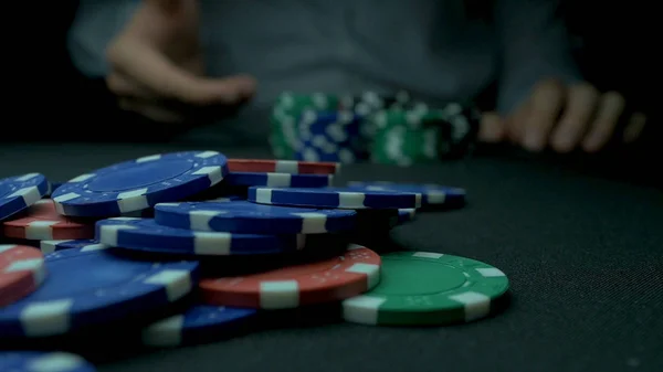 Zbliżenie: człowiek rzuca żetony do pokera w zwolnionym tempie. Zbliżenie dłoni z rzucania żetony do gry na czarnym tle. Zwiększenie jego stawki rzuca żetony na stole do gry w pokera. — Zdjęcie stockowe