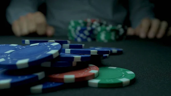 Nahaufnahme eines Mannes, der in Zeitlupe Pokerchips wirft. Nahaufnahme der Hand mit dem Werfen von Glücksspielchips auf schwarzem Hintergrund. Pokerspieler erhöht seinen Einsatz und wirft Spielmarken auf den Spieltisch. — Stockfoto