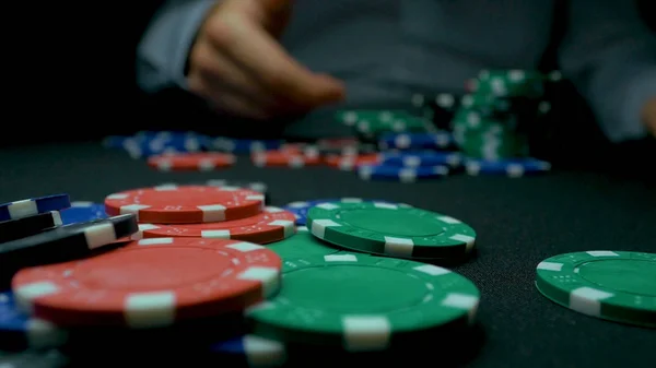 Close-Up of Man Throwing a Poker Chips in slow motion. Close-up of hand with throwing gambling chips on black background. Poker player increasing his stakes throwing tokens onto the gaming table.