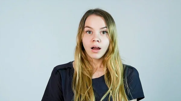 Shocked woman. Young woman touching face with hands and staring at camera while standing against white background — Stock Photo, Image