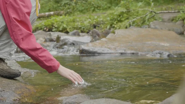 Mujer joven tocando el agua del río en el bosque. Joven turista toca la mano del río — Foto de Stock