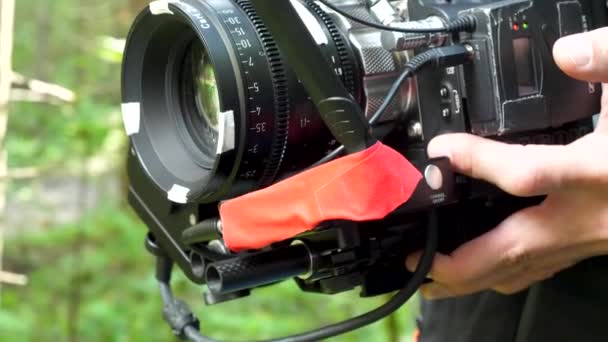 Férfi gazdaság egy kamera a forgatás a film az erdőben. Drága kamera film az erdőben — Stock videók