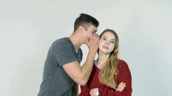 Chica bonita susurrando secreto al oído de su amigo risueño sobre fondo blanco - concepto de amistad — Foto de Stock