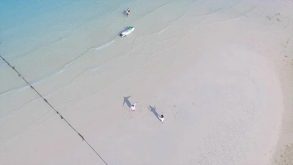 Lyckliga paret tillsammans på stranden. Ungt par njuter av varandra på en strand. En ung man och kvinna har kul Dans som romantiska par på en strand med klarblå himmel och hav. — Stockfoto