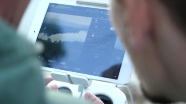 Adam tutarak uzaktan kumanda tablet uçan uçaklar için kullanma. Erkekler eller güzel bir beyaz uzaktan kumanda ile dron işlecinin, uçuş ve çekim görsel gözlem yakın çekim