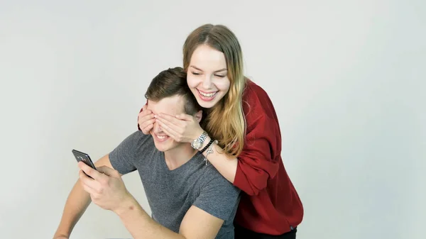 Beautiful happy smiling woman covering eyes with her hands of handsome young man in fun mood — Stock Photo, Image