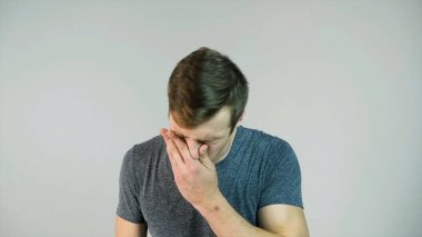 Genç adam beyaz bir arka plan üzerinde ağır çekim hapşırma