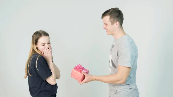 Gelukkige jonge paar met heden op een witte achtergrond. Gelukkig man een geschenk te geven aan zijn vriendin — Stockfoto