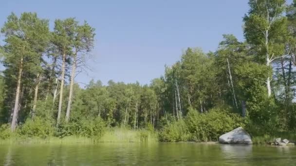 Schön blaues klares Wasser am Ufer des Sees. Waldlandschaft an der Küste spiegelt sich im Wasser — Stockvideo
