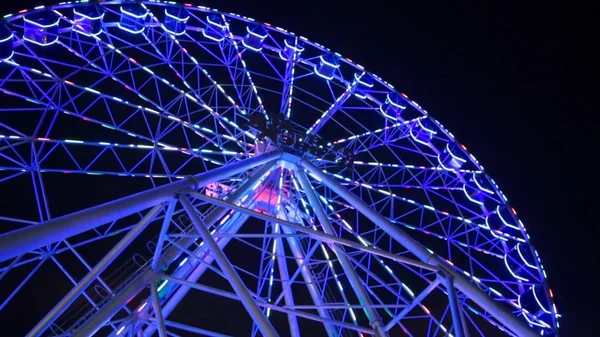 Ferris wheel in blue neon light on dark background, Part of Ferris wheel with blue illumination against a black sky background at night. Ferris wheel by night. Ferris wheel with multi-colored — Stock Photo, Image