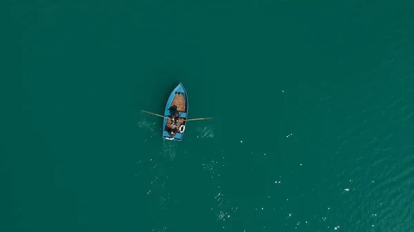 Barco aéreo no lago. Vista aérea em dois homens em um barco em um lago, remou para a costa. Barco solitário no meio do rio, lago. Barco fila única no mar com reflexão na água no — Fotografia de Stock