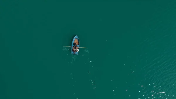 Luchtfoto boot op het meer. Luchtfoto op twee mannen in een boot op een meertje, roeide naar de kust. Eenzame boot in het midden van de rivier, lake. De enkele rij boot op zee met weerspiegeling in het water in de — Stockfoto