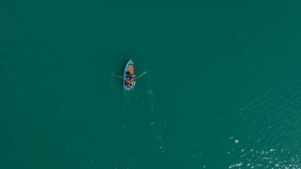 Aerial Boat on the lake. Aerial view on two men in a boat on a lake, rowed to the shore. Lonely boat in the middle of the river, lake. Boat single row on sea with reflection in the water in the