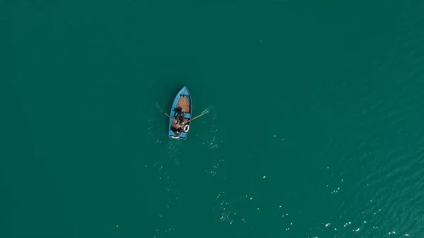 Aerial Boat on the lake. Aerial view on two men in a boat on a lake, rowed to the shore. Lonely boat in the middle of the river, lake. Boat single row on sea with reflection in the water in the