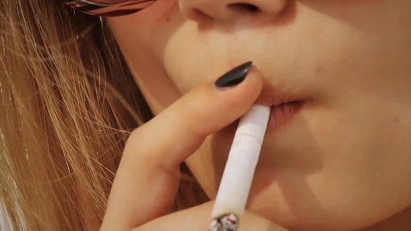 The girl smokes a cigarette closeup. sexy smoking beautiful woman cigarette closeup. Front view face closeup holding a cigarette in lips. Beautiful woman smoking a cigarette — Stock Photo, Image