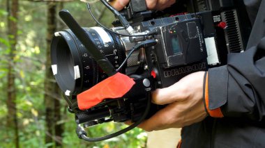 Ormanın içinde bir film filme bir kamera tutan adam. Ormanda film için pahalı kamera