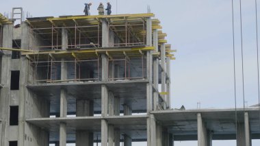 Yapı İnşaat site işi mavi gökyüzü karşı. Bir apartman, inşaat sahasında işçiler