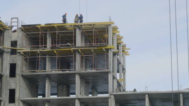 Yapı İnşaat site işi mavi gökyüzü karşı. Bir apartman, inşaat sahasında işçiler