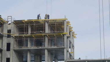 Yapı İnşaat site işi mavi gökyüzü karşı. Bir apartman, inşaat sahasında işçiler