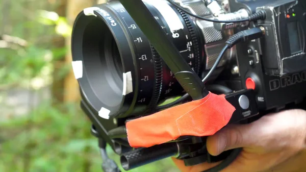 Homem segurando uma câmera filmando um filme na floresta. Câmera cara para filme na floresta — Fotografia de Stock