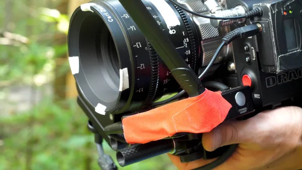 Homem segurando uma câmera filmando um filme na floresta. Câmera cara para filme na floresta — Fotografia de Stock