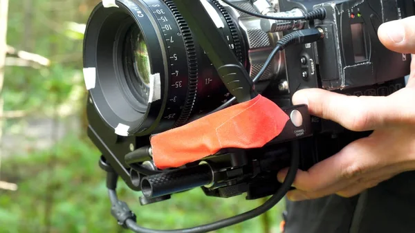 Homem segurando uma câmera filmando um filme na floresta. Câmera cara para filme na floresta — Fotografia de Stock