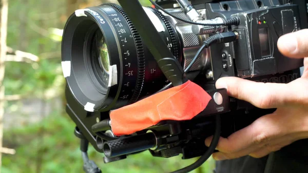 Man holding a camera filming a movie in the forest. Expensive camera for movie in the woods
