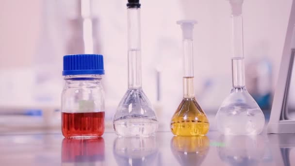 Laboratory flasks and beakers with liquids of different colors on lab table — Stock Video