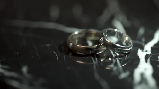 Mooie trouwringen tot uiting op een zwarte glanzende achtergrond. Prachtige sieraden en flitslicht. Ring met diamanten op zwarte achtergrond. — Stockvideo