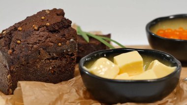 Doğranmış tereyağı, havyar, siyah ekmek. Kaşık ile kırmızı havyar kase dilimlenmiş ekmek, tereyağı ve otlar beyaz arka plan üzerinde hizmet verdi. Kepekli ekmek, tereyağı ve kırmızı havyar, beyaz arka plan